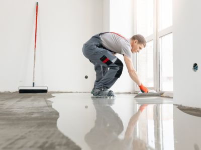 Homme en train de poser une chape liquide pour ses travaux d'intérieur.