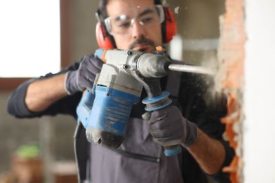 Personne utilisant un marteau perforateur de location pour ses travaux.